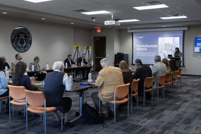 Participants gather around tables for an education-sector presentation.