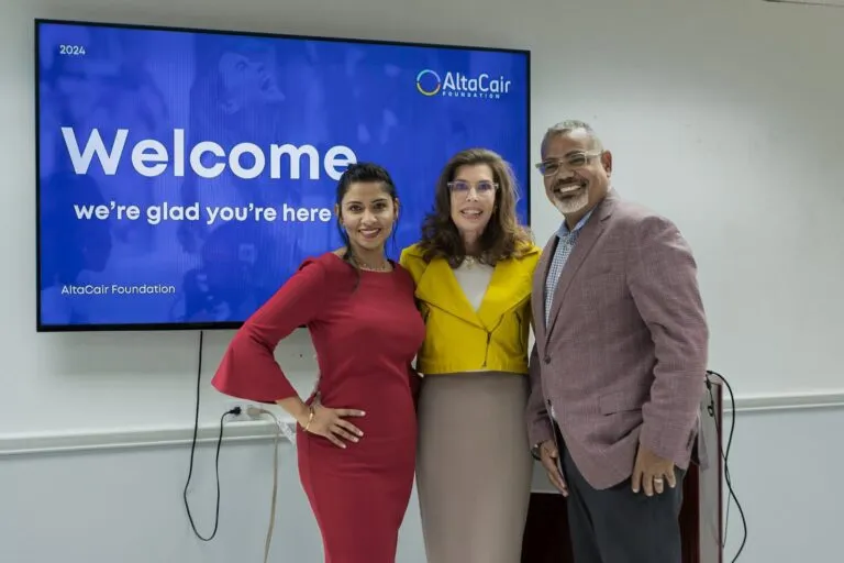 Three participants stand together in front of the welcome display.