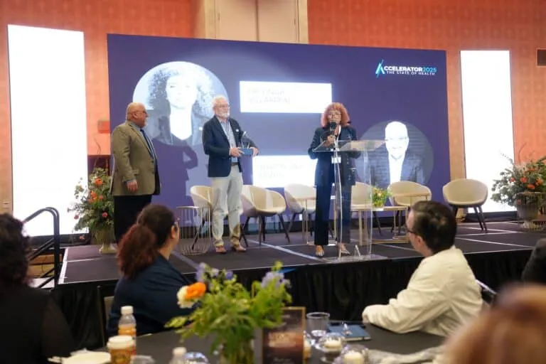 A standing speaker addresses fellow panelists and the audience.